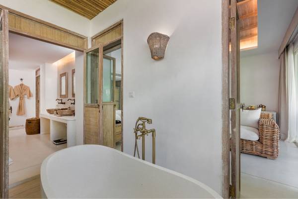 Das Badezimmer im Eden Beach Khao Lak Resort & Spa mit Badewanne, Waschbecken und Holzmöbeln.