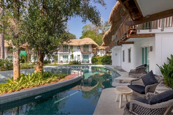 Außenbereich des Eden Beach Khao Lak Resort & Spa mit Swimmingpool und Sonnenliegen.