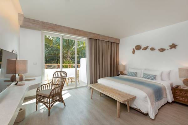 Schlafzimmer im Eden Beach Khao Lak Resort & Spa mit Bett, Nachttischen und Balkon.