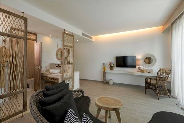 Innenansicht einer Suite im Eden Beach Khao Lak Resort & Spa mit modernem Design, Sofa, Tisch und Fernseher.