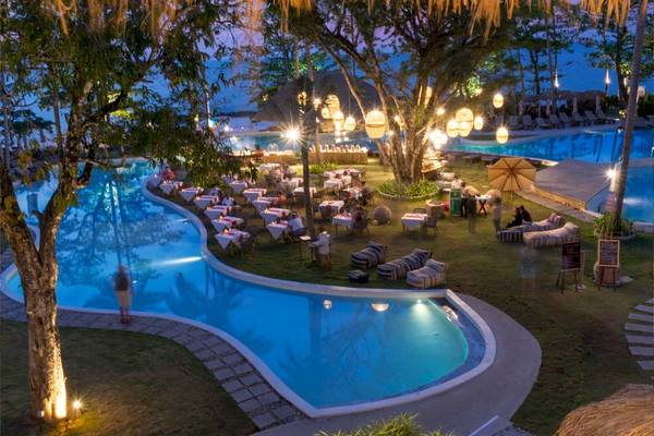 Poolbereich des Eden Beach Khao Lak Resorts bei Nacht mit vielen Tischen und Stühlen