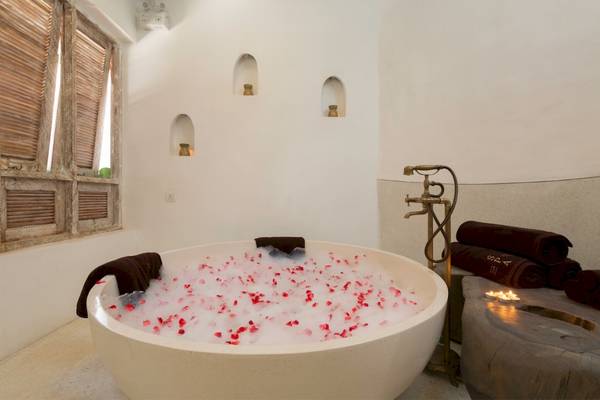 Eine weiße Badewanne mit Rosenblättern und Seifentüchern im Eden Beach Khao Lak Resort & Spa.