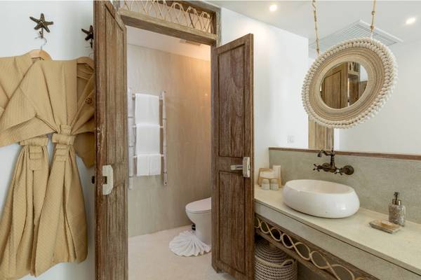 Badezimmer im Eden Beach Khao Lak Resort & Spa mit offener Tür, Toilette, Waschbecken und Spiegel.