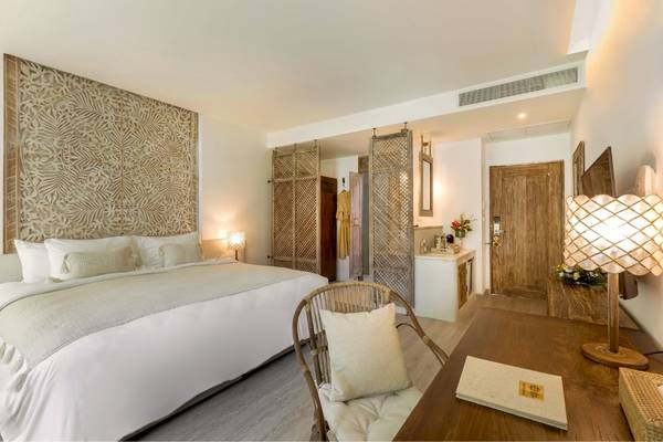 Schlafzimmer im Eden Beach Khao Lak Resort & Spa mit einem großen Bett, dekorativen Wänden und Möbeln.
