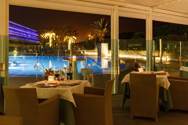 Ein abendlicher Blick auf das Hotelrestaurant von Santa Monica Suites mit Tischen und Stühlen, die den Pool überblicken.