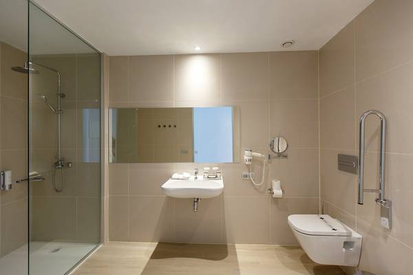Badezimmer im Santa Monica Suites Hotel mit Dusche, Waschbecken und Toilette.
