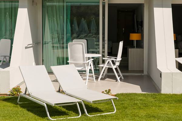 Terrasse im Santa Monica Suites mit weißen Liegestühlen und Tisch