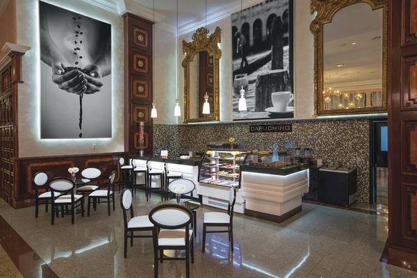 Innenansicht des Cafés im Riu Palace Las Americas Hotel mit Sitzgelegenheiten und einer Theke.