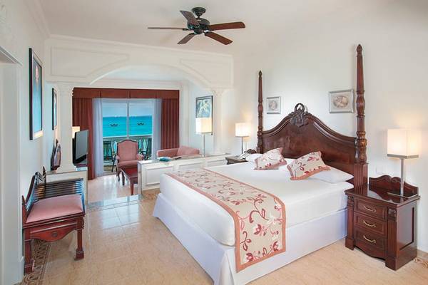 Suite Zimmer im Riu Palace Las Americas mit Meerblick, großes Bett, Balkon und modernen Möbeln.