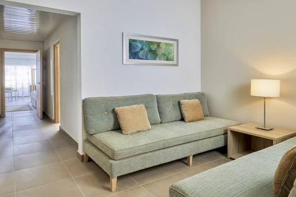 Hotelzimmer im Jaz Maraya Resort mit grünem Sofa, Tischlampe und Gemälde an der Wand.