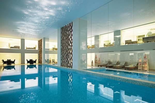 Innenpool im Mitsis Alila Resort & Spa mit modernen Möbeln und Glaswänden.