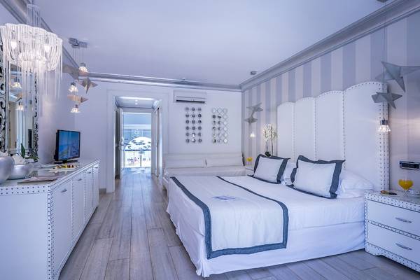 Schlafzimmer im Mitsis Alila Resort & Spa mit Bett, Möbeln und Fernseher.