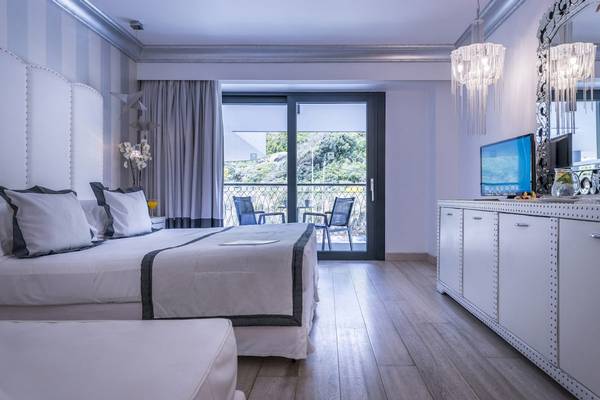 Schlafzimmer im Mitsis Alila Resort & Spa mit Doppelbett, Balkon und Fernseher.