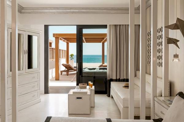 Innenansicht eines Zimmers im Mitsis Alila Resort & Spa mit offenem Balkon und Meerblick.