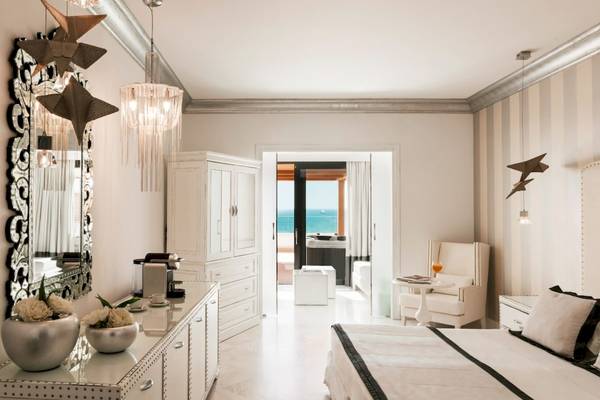 Schlafzimmer im Mitsis Alila Resort & Spa mit Blick auf das Meer und modernen Möbeln.