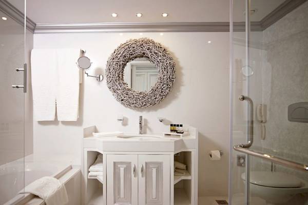Badezimmer im Mitsis Alila Resort & Spa mit Badewanne, Waschbecken und Dusche.