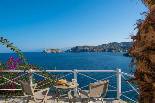 Terrasse mit Meerblick im Peninsula Resort & Spa mit zwei Stühlen, einem Tisch und einer Hut auf dem Tisch.