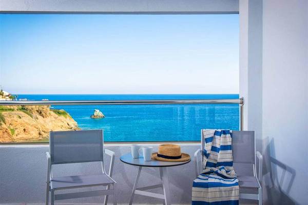 Balkon mit Meerblick im Peninsula Resort & Spa mit zwei Stühlen, einem Tisch und einem Handtuch.