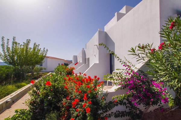 Außenansicht des Peninsula Resort & Spa mit weißen Gebäuden und bunten Blumen.