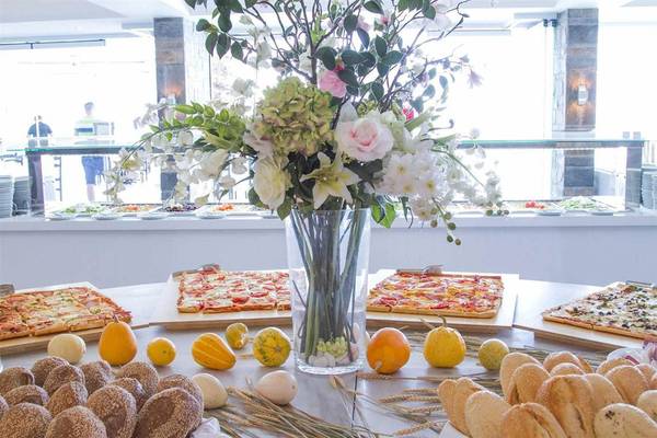 Ein Tisch im Peninsula Resort & Spa mit einer Vase voller Blumen, verschiedenen Pizzen und Brotsorten.