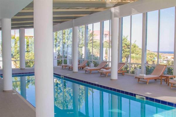 Ein Hallenpool im Innenbereich des Peninsula Resort & Spa mit Loungeliegen und Glaswänden.