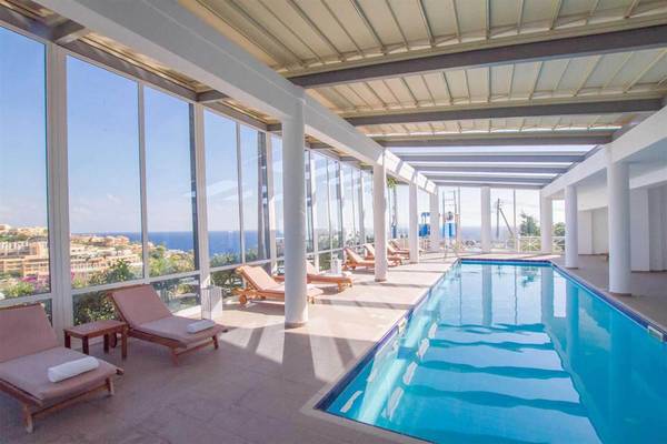 Innenpool im Peninsula Resort & Spa mit Blick auf die Stadt und das Meer.