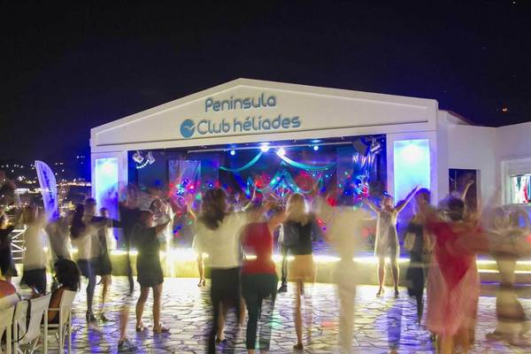 Eine nächtliche Club Heliades Veranstaltung im Peninsula Resort & Spa mit tanzenden Gästen und einer beleuchteten Bühne.