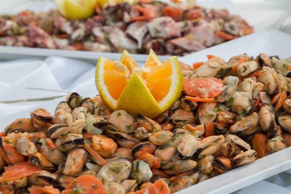 Muschelsalat im Peninsula Resort & Spa mit Zitronenscheiben auf einem weißen Teller.