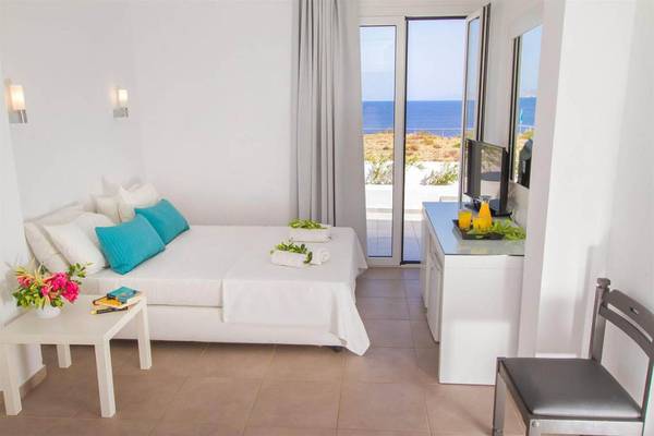 Hotelzimmer im Peninsula Resort & Spa mit Blick auf das Meer, einem Doppelbett, Büchern, einer Pflanze und einer Terrasse.