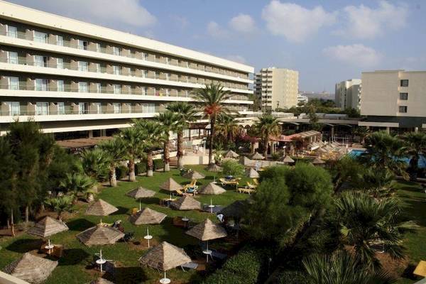 Außenansicht des Blue Sea Beach Resorts mit vielen Palmen und Sonnenschirmen im Garten