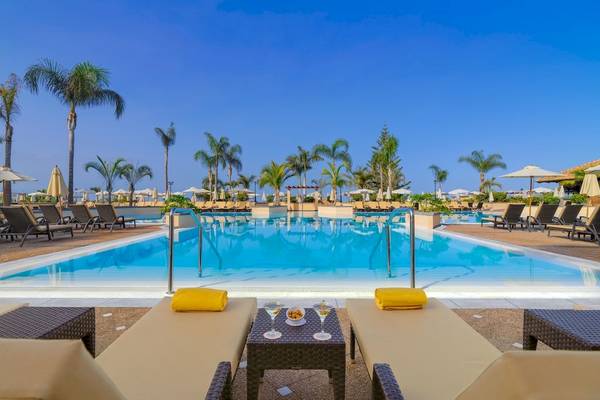 Außenpoolbereich des GF Gran Costa Adeje Hotels mit Loungeliegen und Cocktails.