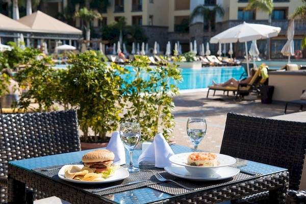 Tisch mit Essen und Getränken am Pool im GF Gran Costa Adeje Hotel