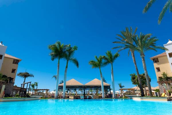 Außenpoolbereich des GF Gran Costa Adeje Hotels mit Palmen und Sonnenschirmen.