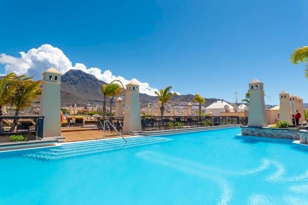 Ein Swimmingpool im GF Gran Costa Adeje Hotel mit Blick auf einen Berg und die Stadt.