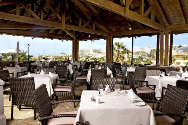 Innenansicht des Restaurants im GF Gran Costa Adeje Hotel mit gedeckten Tischen und Stühlen.