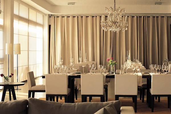 Ein eleganter Speisesaal im Almyra Hotel mit gedecktem Tisch, Kristallkronleuchter und beige Vorhängen.