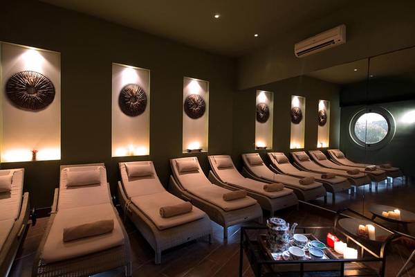 Relaxationsbereich im Sea Side Resort & Spa mit mehreren Liegen, beleuchteten Wandkunstwerken und einem runden Fenster.