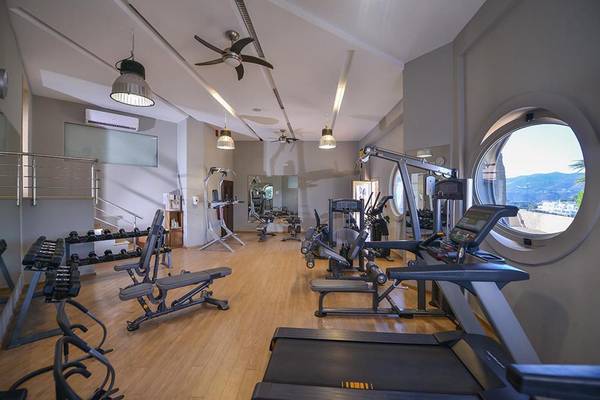 Fitnessstudio im Sea Side Resort & Spa mit verschiedenen Geräten und Panoramafenster.