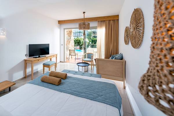 Schlafzimmer im Sea Side Resort & Spa mit Bett, Fernseher, Tisch, Spiegel und Möbeln.