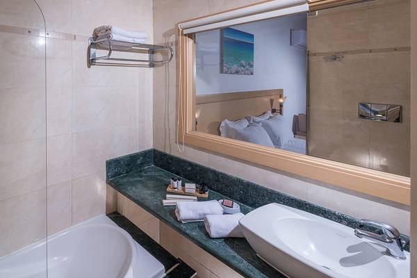 Badezimmer im Sea Side Resort & Spa mit Badewanne, Spiegel und Waschbecken.