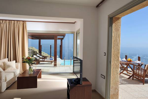 Wohnzimmer mit Meerblick im Sea Side Resort & Spa, mit Couch, Fernseher, Tisch und Pool