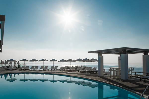 Außenpool des Sea Side Resort & Spa mit Sonnenschirmen und Liegestühlen, Blick auf das Meer.