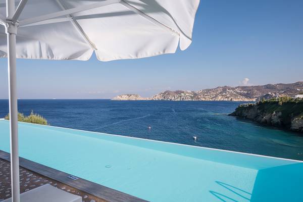 Ein Pool mit einem Blick auf das Meer und eine Insel unter einem weißen Schirm.