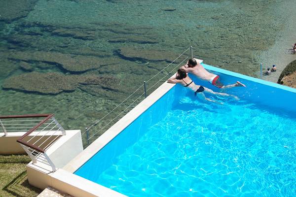 Paar schwimmt im Pool am Meer im Sea Side Resort & Spa
