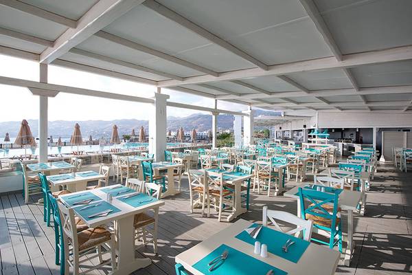 Terrasse-Restaurant im Sea Side Resort & Spa mit Blick auf den Pool und Berge.