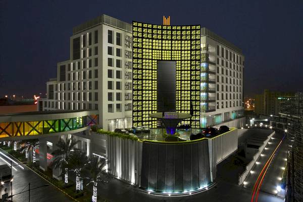 Grand Millennium Muscat Hotel bei Nacht mit beleuchteten Fassaden und Wasserfall