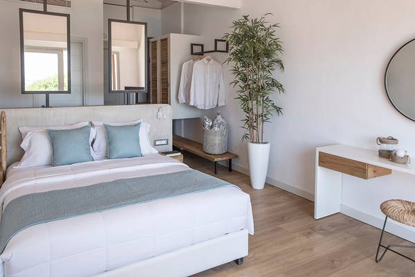 Schlafzimmer im Sea Side Resort & Spa mit weißem Bett, blauen Kissen und Holzboden.