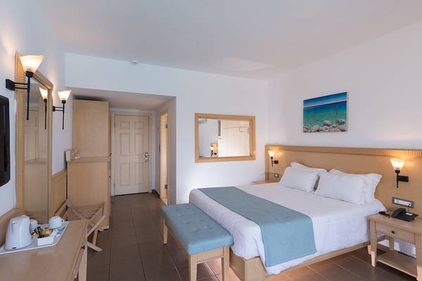 Zimmer im Sea Side Resort & Spa Hotel mit Bett, Spiegel und Dekoration.