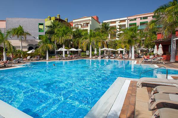 Außenpool des Lopesan Villa del Conde Resort mit Gästen und Palmen im Hintergrund.