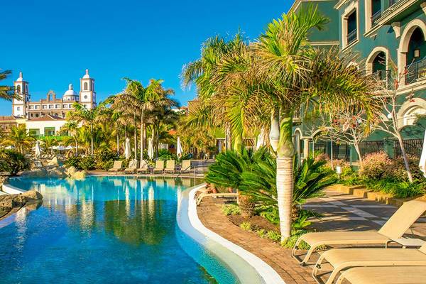 Außenpool des Lopesan Villa del Conde Resort mit Palmen und Liegestühlen.